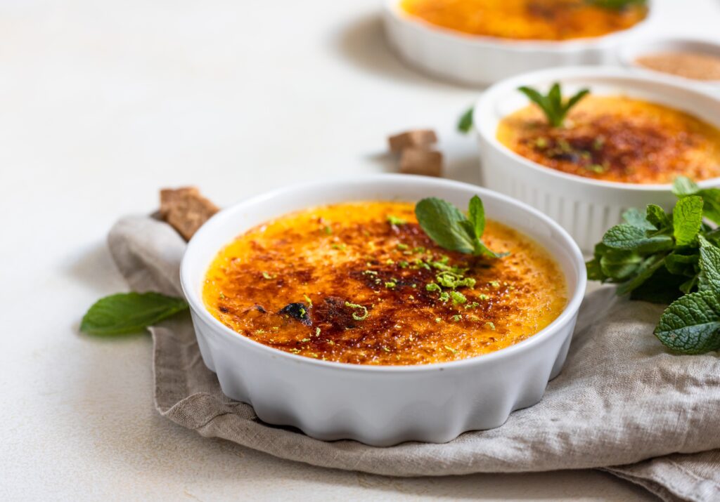 Golden caramelized crust on a crème brûlée garnished with fresh mint leaves