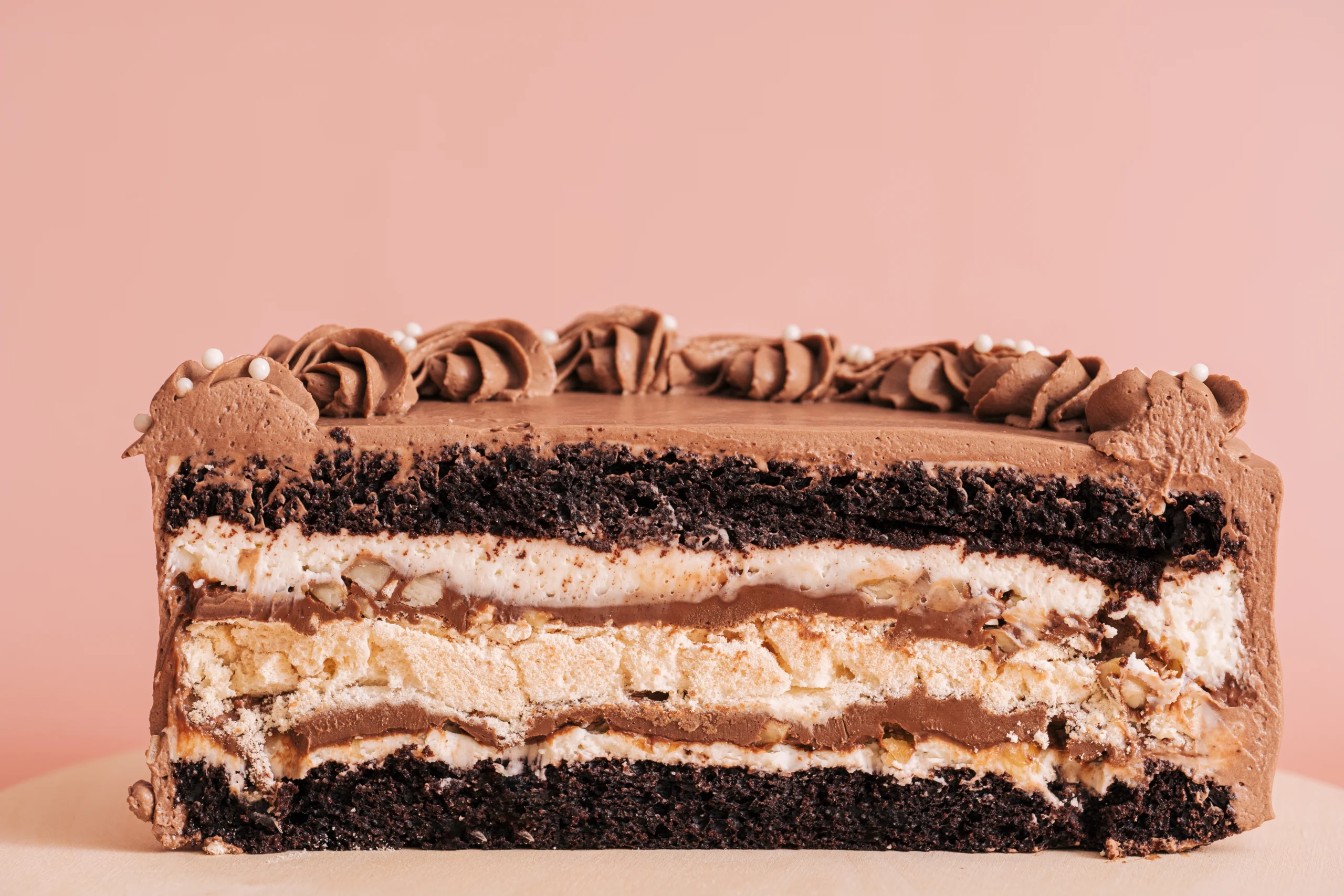 A slice of Swiss chocolate cake topped with chocolate ganache and raspberries on a white plate.