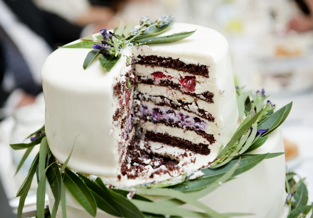 Elegant three-tier white wedding cake decorated with fresh flowers and greenery